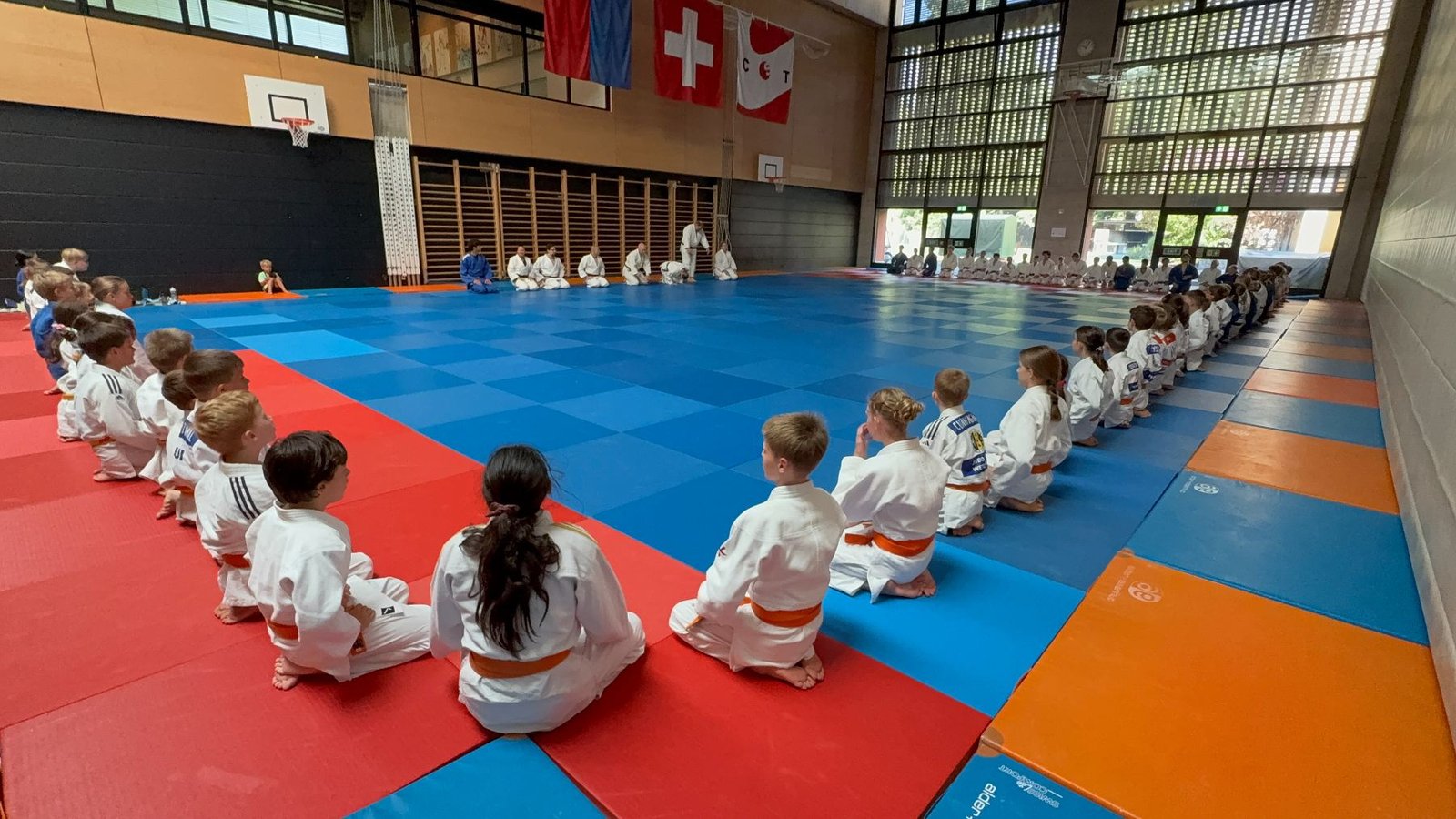 Judoka sitzen im Kreis auf der Matte vor dem Training in Tenero